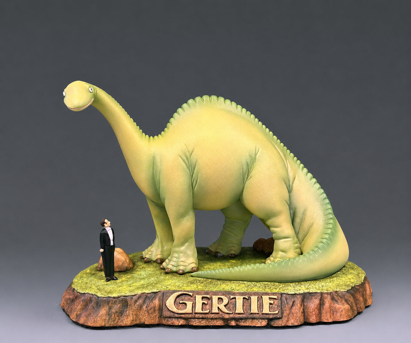 Dinosaur figurine named 'Gertie' with a small human figure of cartoonish Winsor McCay.